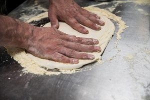 Pizzabodem maken met je handen van pizzadeeg
